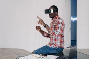 Young afro businessman has virtual lesson. Virtual reality goggles using for business. photo