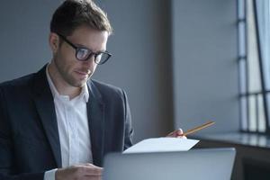 Serious male professional analyzing documents at workplace. Business and job concept photo