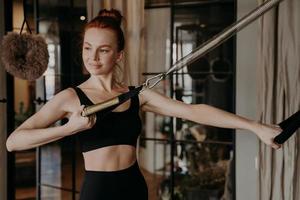 Training time of healthy happy ginger woman, exercising on cadillac reformer photo