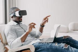 Relaxed businessman clicks virtual buttons. Gestures of african american man in vr glasses.