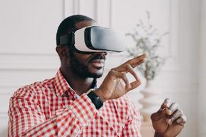 Young african businessman wearing VR glasses touching 3d objects, interacting with virtual reality photo