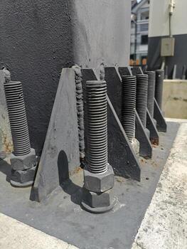 Bolts and nuts on the cement base. Several gray double bolts are firmly fixed to a steel column to a concrete base. Close focus and select an object photo
