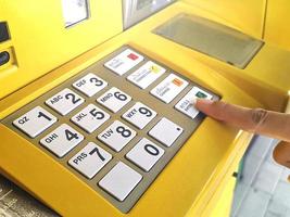 Close-up of hand entering PIN pass code on ATM bank machine keypad photo