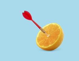 fruta naranja con objetivo circular marcado y dardo rojo sobre fondo azul pastel. concepto de comida y fruta de idea mínima. una idea creativa para producir un trabajo dentro de una comunicación publicitaria de marketing foto