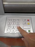Close-up of hand entering PIN pass code on ATM bank machine keypad photo