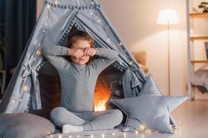 despertando linda niña jugando en la carpa que está en la habitación doméstica foto