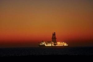 majestuosa vista lejana del barco que está en el océano al atardecer foto