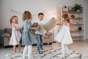 Pillow fight at birthday party. Group of children is together at home at daytime photo