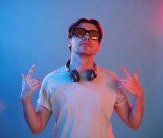 Showing gestures. Man standing in the studio with neon light photo