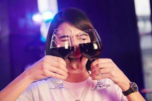 mujer positiva sosteniendo vasos con bebidas y sonriendo foto