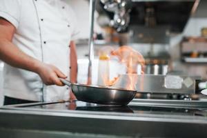 método de cocción encendiendo harina. chef profesional preparando comida en la cocina foto