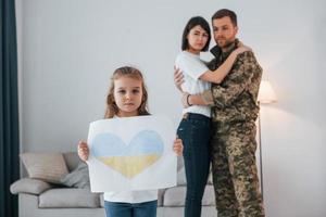 detener la guerra en ucrania concepción. soldado en uniforme está en casa con su esposa e hija foto