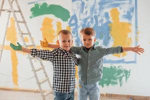 Standing together. Two boys painting walls in the domestic room photo