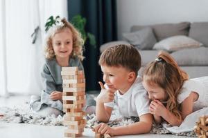 jugando al juego de la torre de madera. grupo de niños está juntos en casa durante el día foto