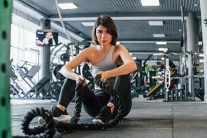 With special equipment. Woman in sportive clothes with slim body type is in the gym photo