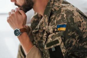 Ukrainian flag. Soldier in uniform is indoors in the domestic room photo