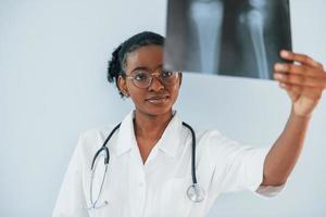 X-ray with picture of bones. Young african american woman is against white background photo