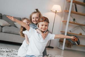 Boy is in aviator glasses. Group of children is together at home at daytime photo