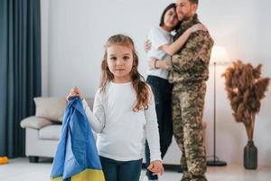 Ukrainian's hard times. Soldier in uniform is at home with his wife and daughter photo