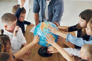 Touching the Earth globe. Group of children students in class at school with teacher photo