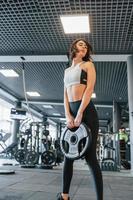 Modern gym. Woman in sportive clothes with slim body type photo