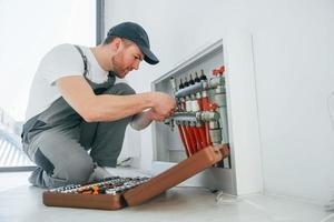 With special tools. Repairman is working indoors in the modern room photo