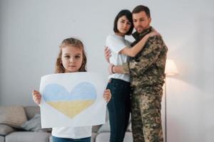 Stop war in Ukraine conception. Soldier in uniform is at home with his wife and daughter photo