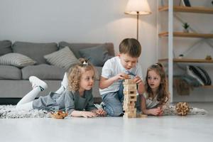 jugando al juego de la torre de madera. grupo de niños está juntos en casa durante el día foto