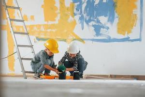 Friends together indoors. Two boys painting walls in the domestic room photo