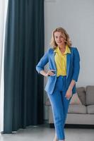 Woman in formal blue and yellow colored trouser suit is indoors photo