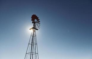 View of windmill that is against clear blue sky with sunlight photo