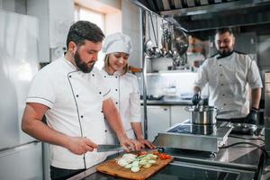 equipo haciendo ensalada. chef profesional preparando comida en la cocina foto