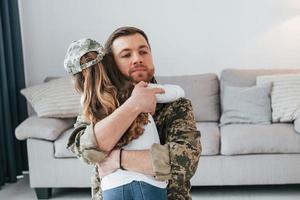 Embracing each other. Soldier in uniform is at home with his little daughter photo