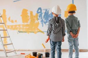 Conception of imagination, art. Two boys painting walls in the domestic room photo