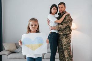 Stop war in Ukraine conception. Soldier in uniform is at home with his wife and daughter photo