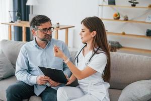 Working with mature man. Professional nurse is in white coat is in the office photo