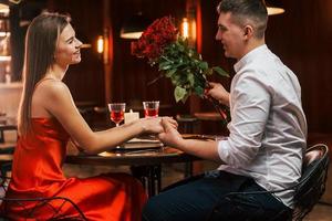 hombre dando hermosas flores. pareja romántica cenar en el restaurante foto