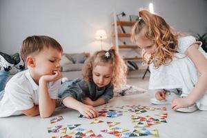 sentado en el suelo y jugando. grupo de niños está juntos en casa durante el día foto