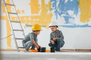 Blue and yellow colored background. Two boys painting walls in the domestic room photo