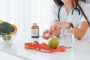 Pills and apple. Professional medical worker in white coat is in the office photo