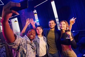 Making selfie. Group of friends having fun in the night club together photo