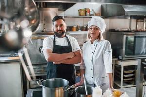 Man and woman standing and posing. Professional chef preparing food in the kitchen photo