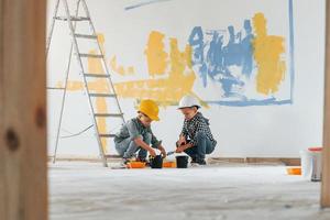Blue and yellow colored background. Two boys painting walls in the domestic room photo