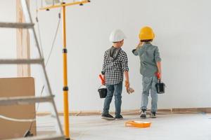 Cheerful kids. Two boys painting walls in the domestic room photo