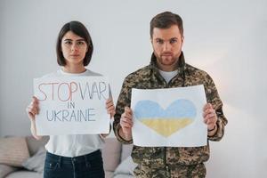 Stop war in Ukrane. Soldier in uniform is at home with his wife photo