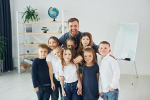 Standing together. Group of children students in class at school with teacher photo