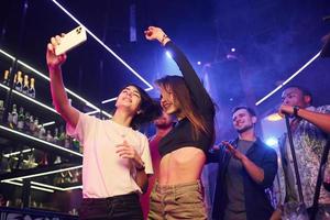 Two women making selfie. Group of friends having fun in the night club together photo