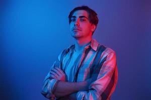 Arms crossed. Man standing in the studio with neon light photo