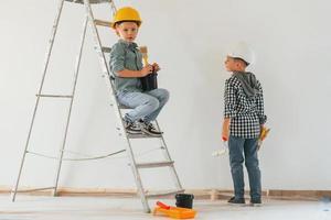 Rear view. Two boys painting walls in the domestic room photo