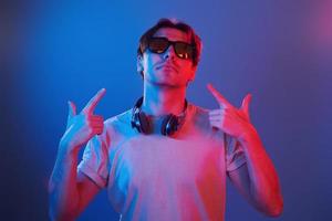 Showing gestures. Man standing in the studio with neon light photo